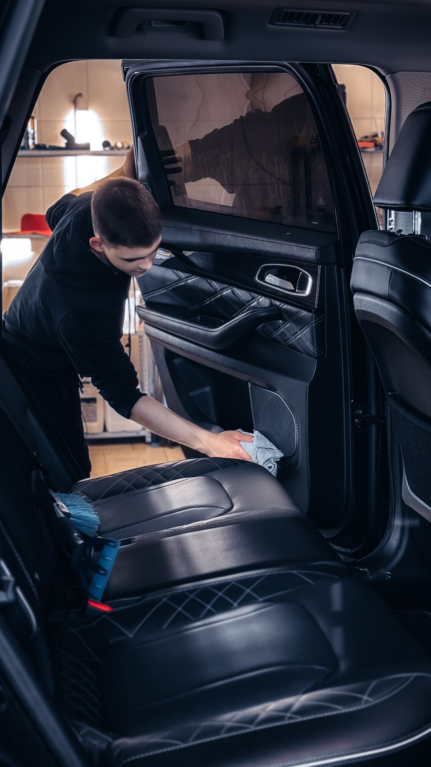 Stock photo of a detailer carefully wiping a vehicle interior